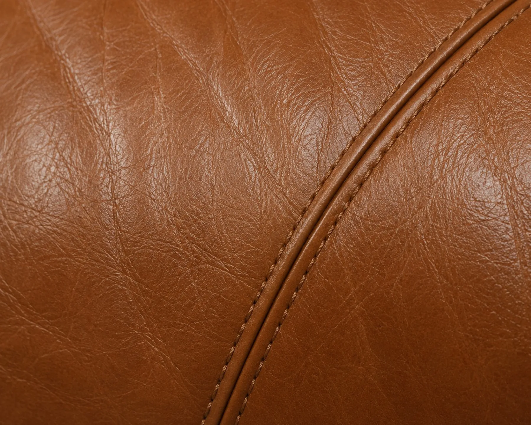 A repaired seam area on a tan leather cushion reflecting light at the same rate as the surrounding panel