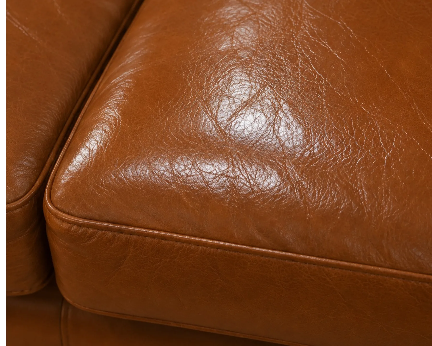 A repaired area on a tan leather sofa arm reflecting light more brightly than the panel around it