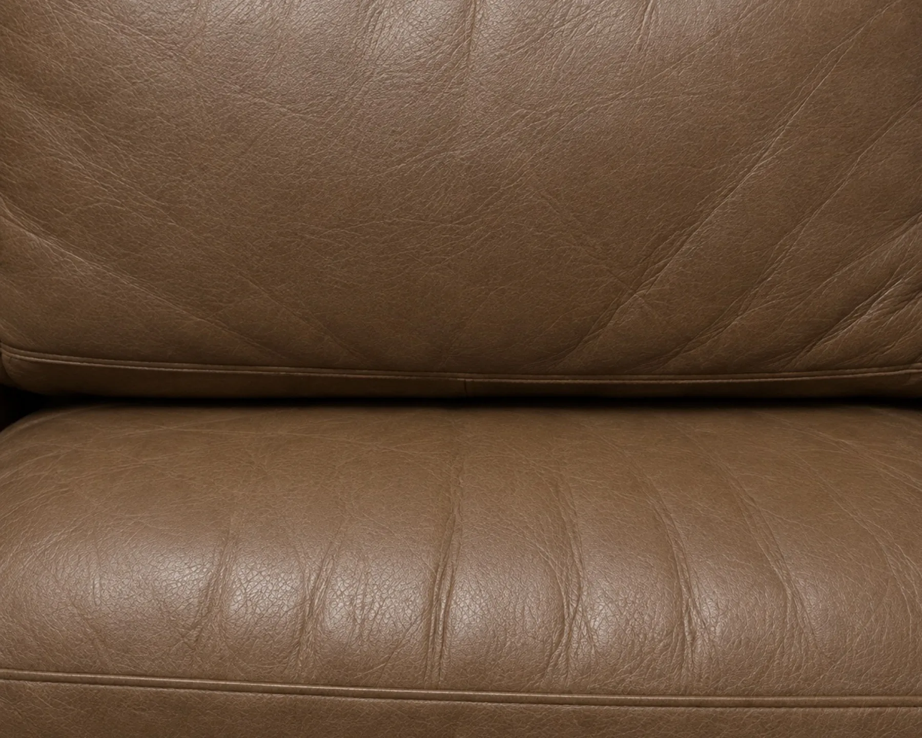 A pale leather seat back gone dull and flat at the head contact point compared with the surrounding panel