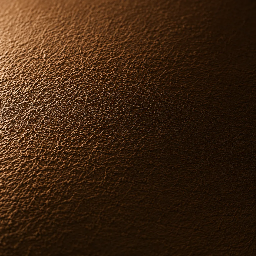 Nubuck leather under raking side light, exaggerating the nap texture and every surface mark