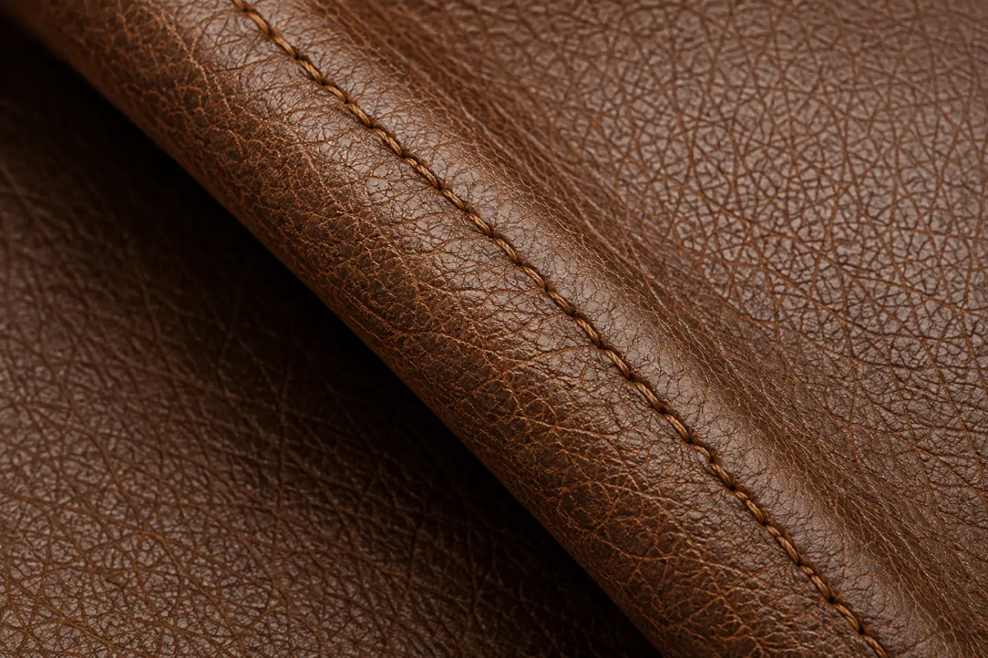 A coated split panel rolled back on its stitched seam, the fold line that flexing works a crack open along