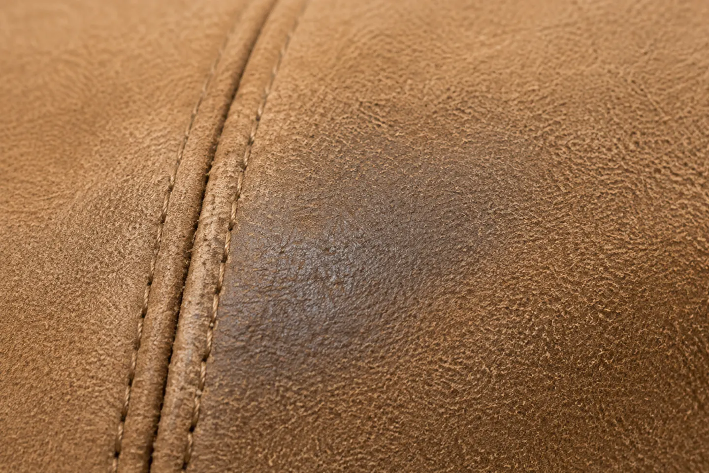 Split leather buffed into a suede nap, the soft pile catching the light along a stitched seam