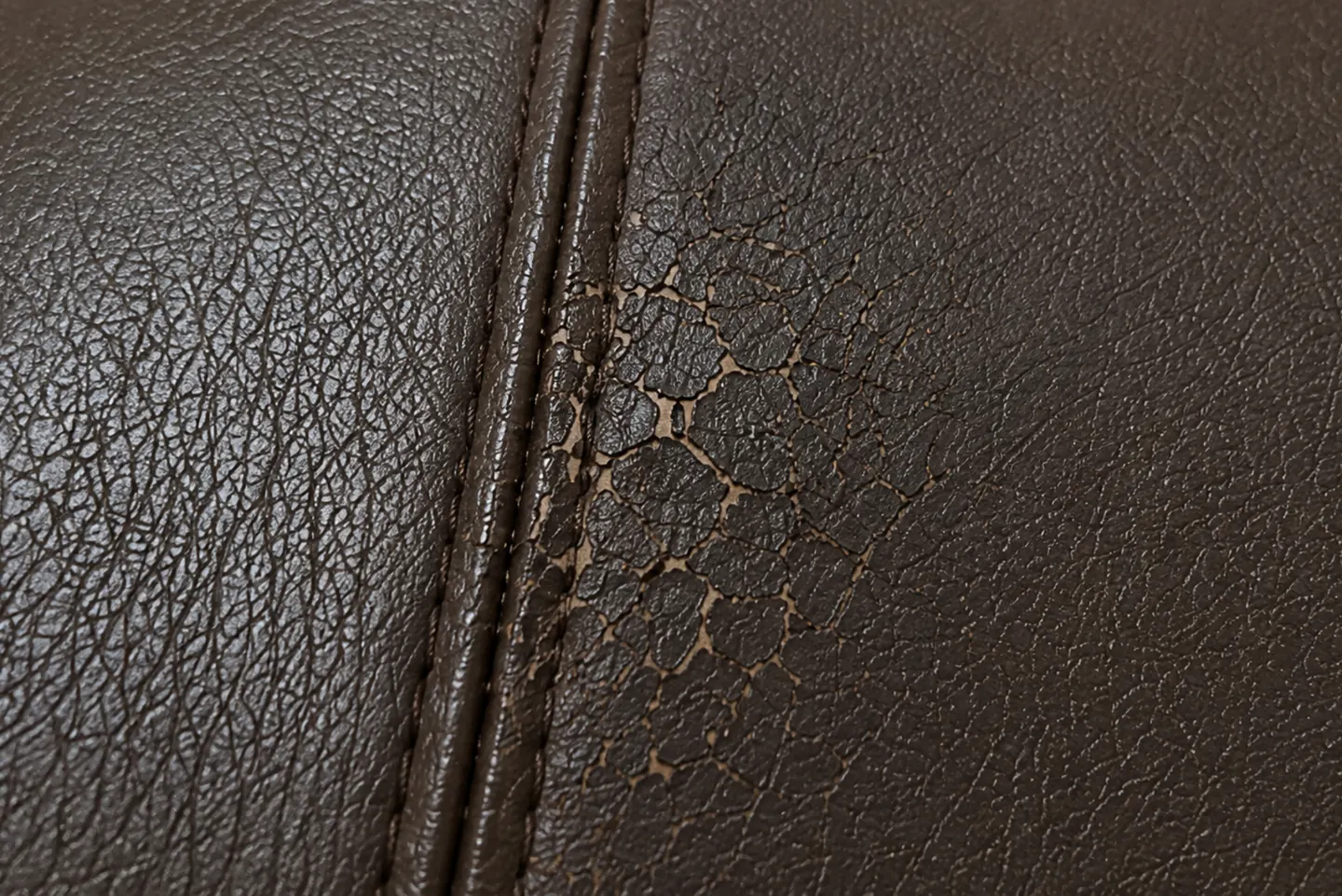 A polyurethane film over a split, crazed into a fine web of cracks beside a stitched seam