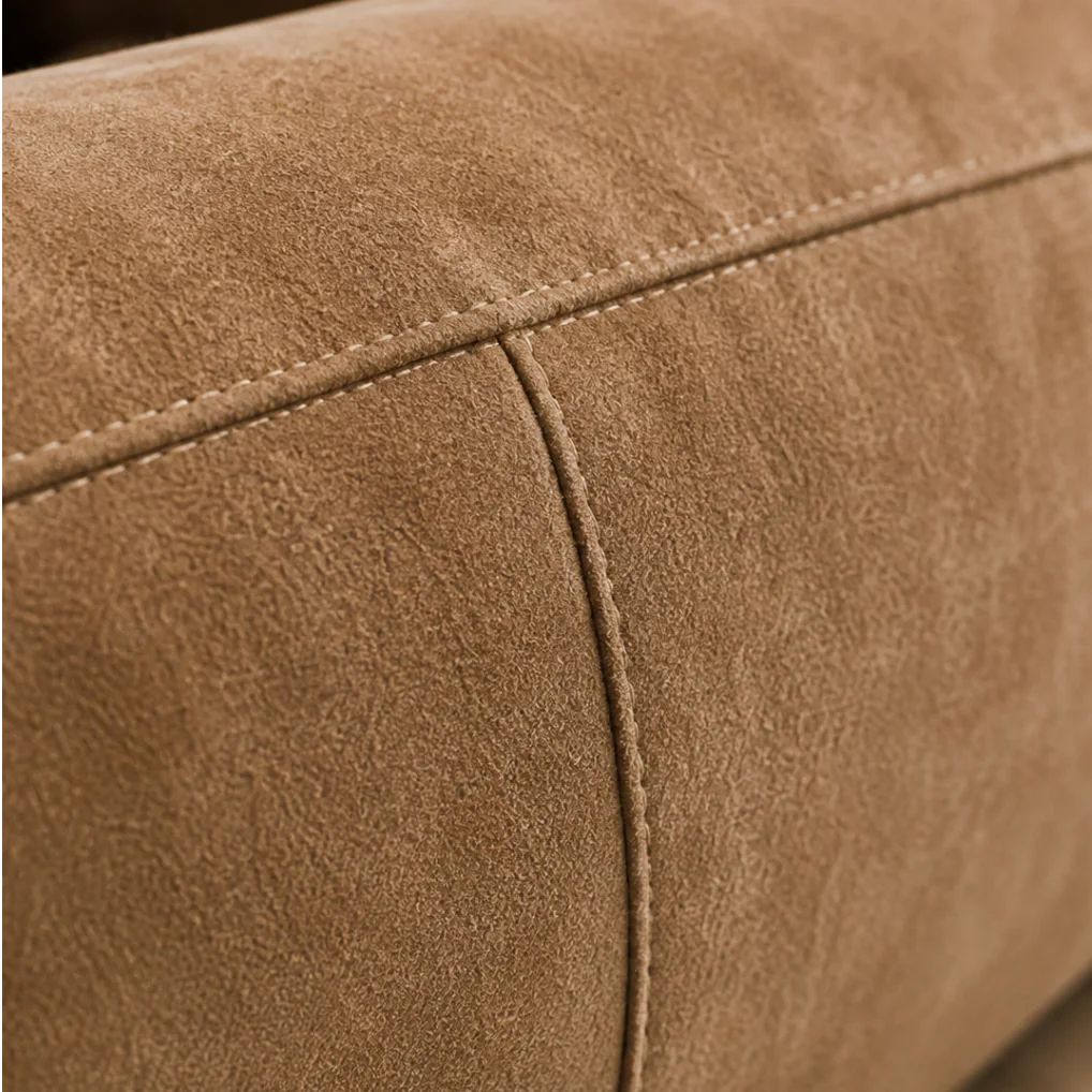 Macro of a suede cushion corner where two stitched seams cross, the nap darker in the fold