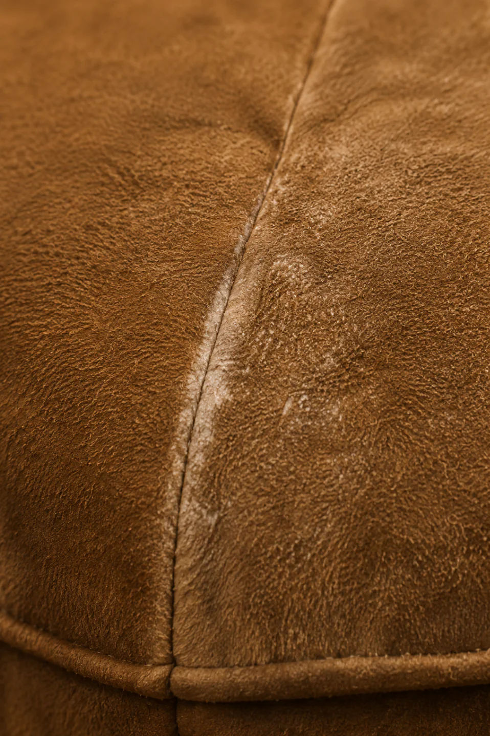 A piped suede seam rubbed smooth and shiny along its ridge, where the raised fibre has gone and the bare split is showing