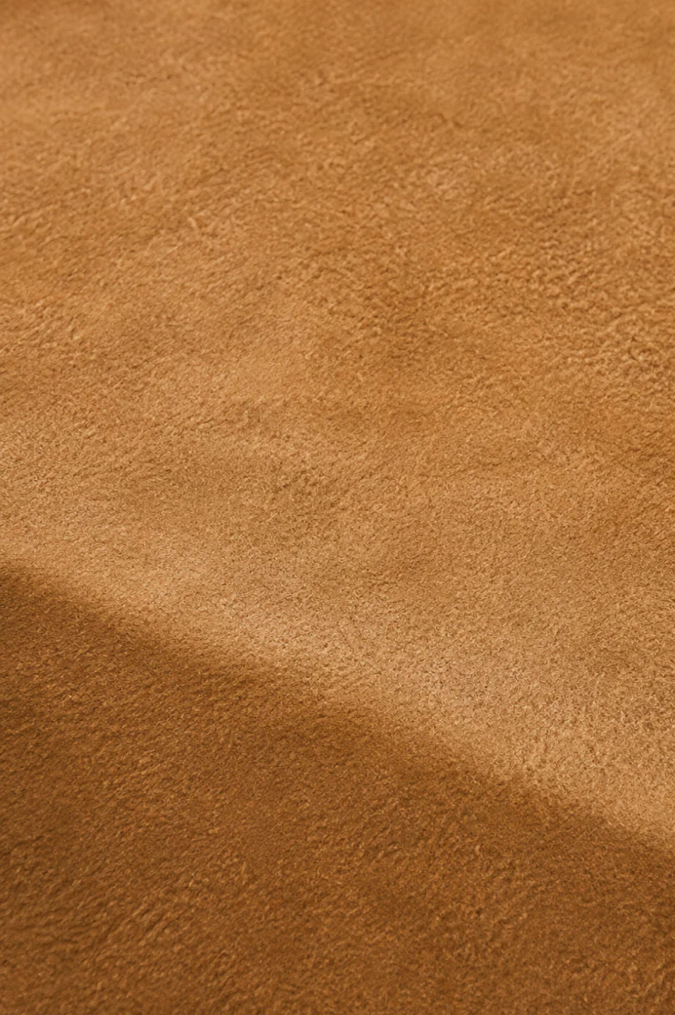 A suede panel faded flat and chalky above a crisp straight line, with the shaded original colour still full-strength below it