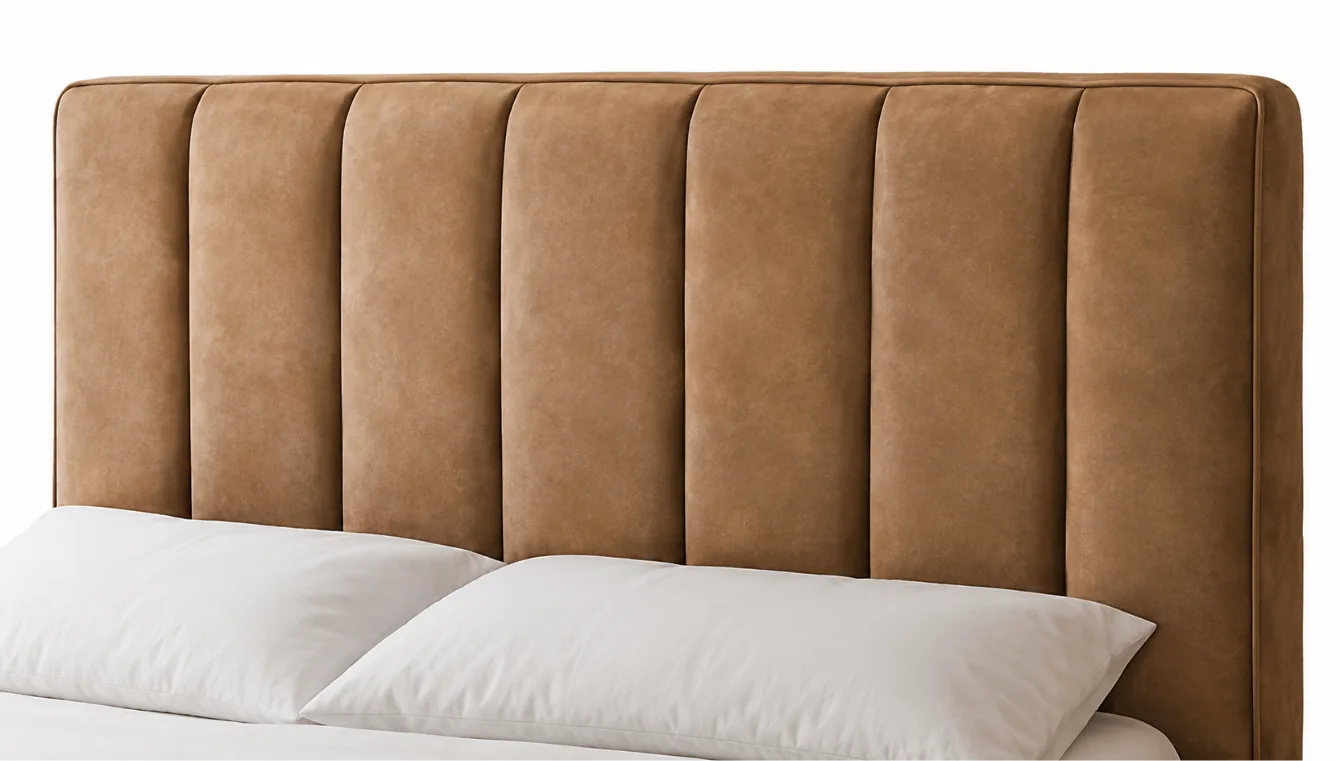 A suede headboard in fluted vertical panels above white pillows, with no contact surface at all
