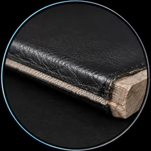 Cut edge of an upholstered panel wrapped over a timber frame, a dark surface film sitting on a distinctly paler backing layer beneath it