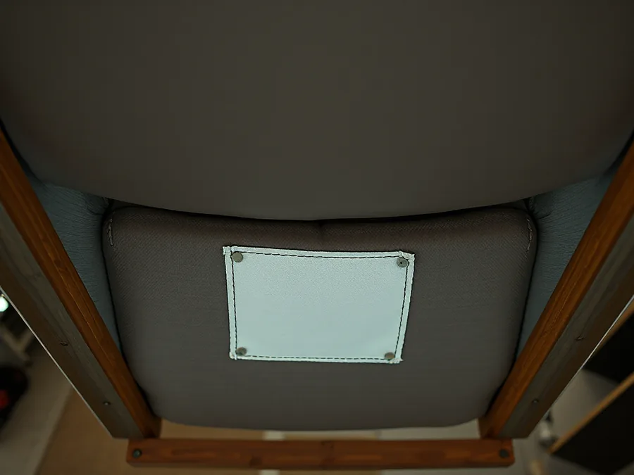 A flammability certification label attached beneath an upholstered commercial seat