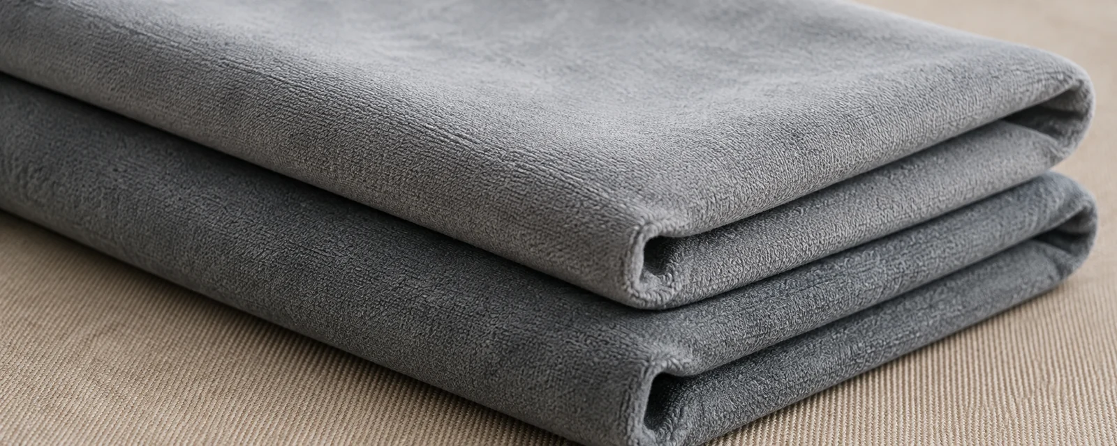 Grey microfiber upholstery fabric folded, showing its smooth brushed surface