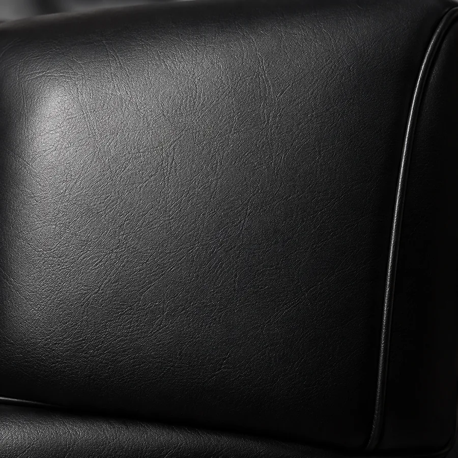 A plain black leather cushion with a piped edge and no tufting