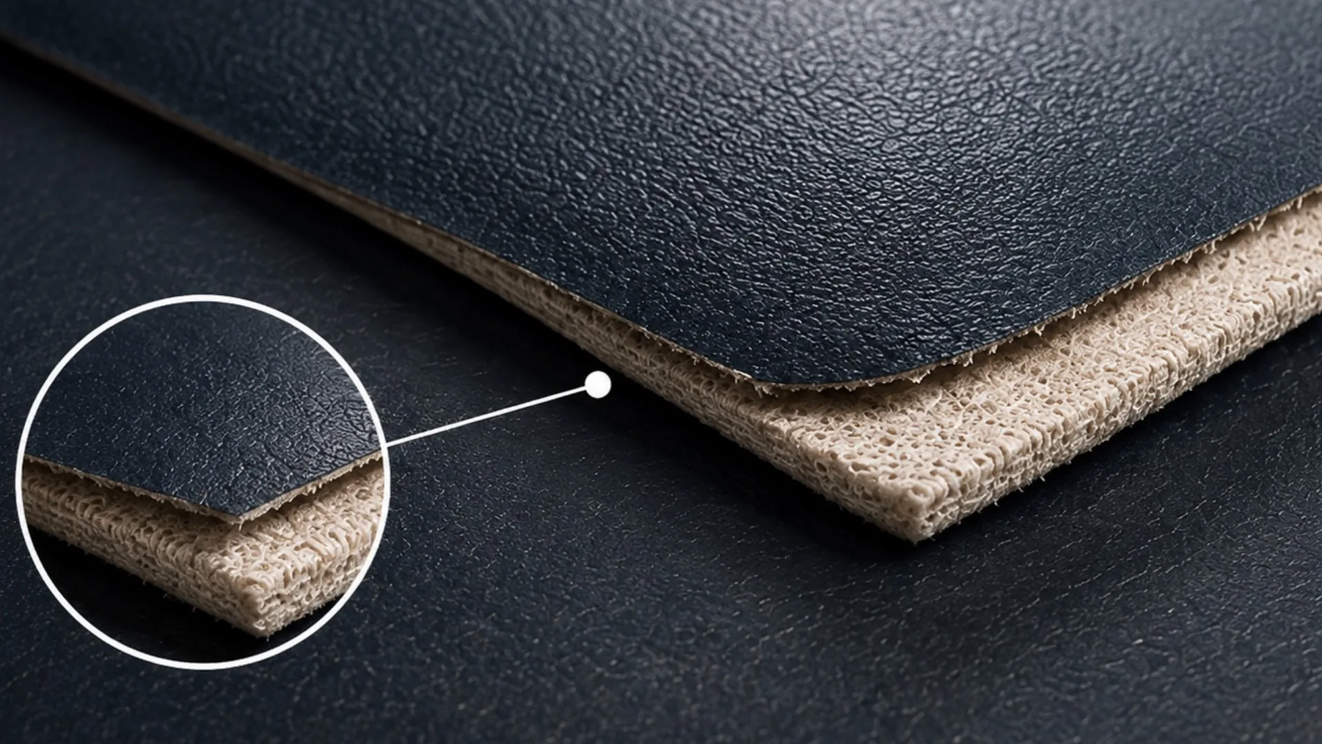 A cut sheet of navy vinyl lifted at one corner, with a magnified inset of the same edge: a grained coloured film sitting on a pale woven backing, and a visible bond line between the two