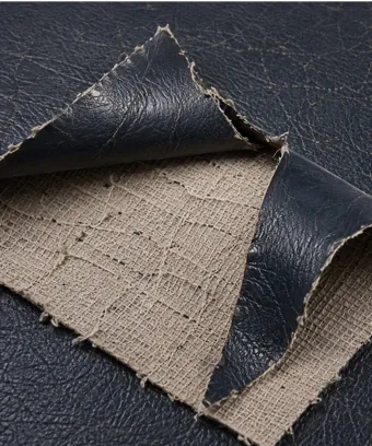 Black vinyl film lifting away from its fabric backing in a loose sheet, leaving the woven layer bare