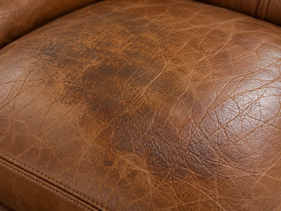 Darkened patch of body oil on the headrest of a tan aniline leather sofa