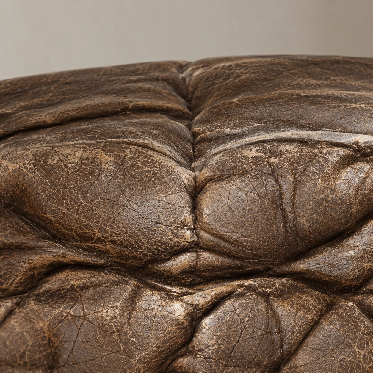 Dry, cracked leather across a tufted Arhaus-style cushion