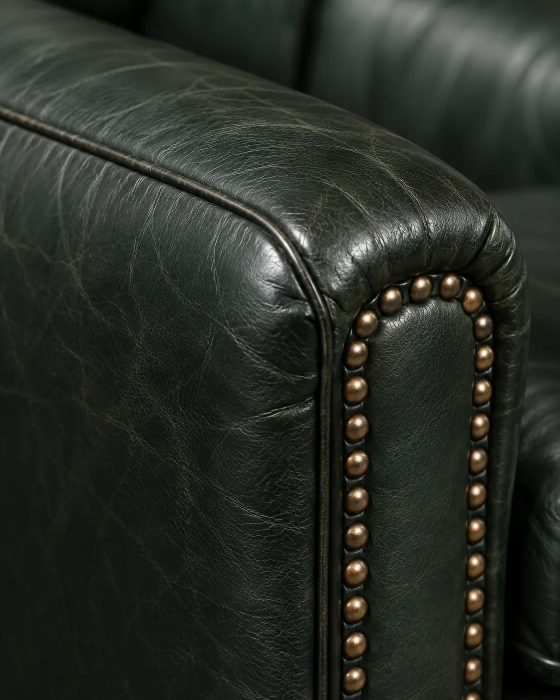 A dark green Chesterfield arm with brass nailhead trim