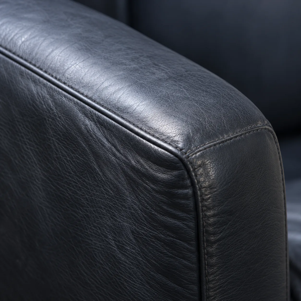 A black leather armrest that has flattened and lost its rounded profile