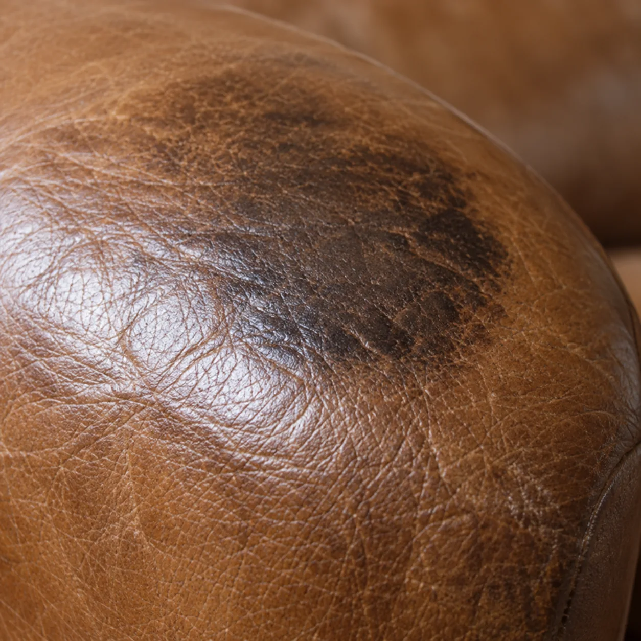 A dark greasy patch worn into the leather of an armrest