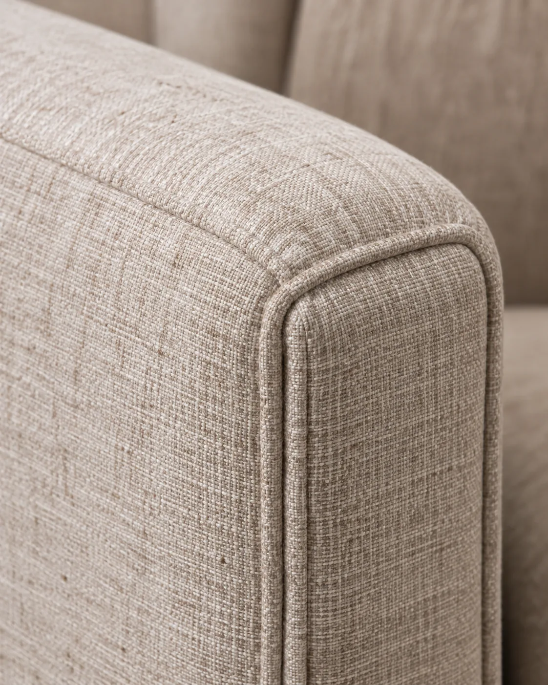 The beige woven fabric arm of an armchair