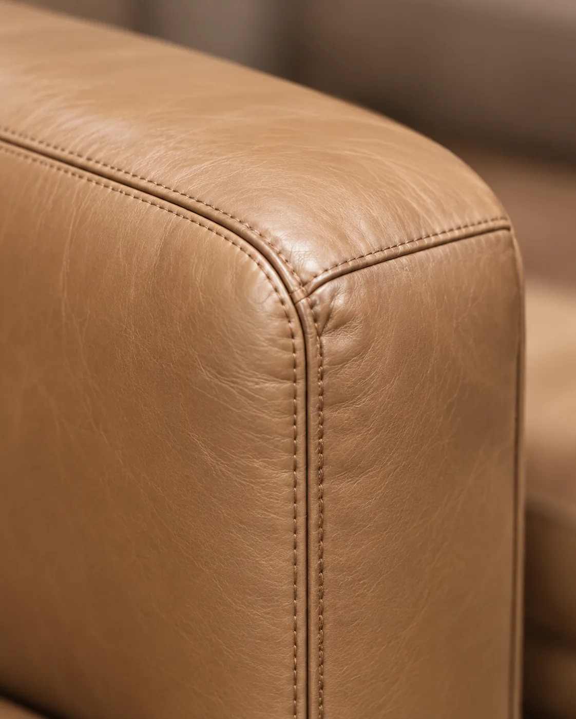 The stitched camel leather edge of an ottoman