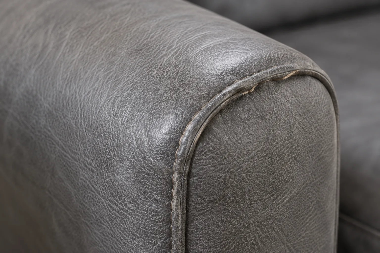 A grey leather armrest with its seam being restitched and the filling rebuilt