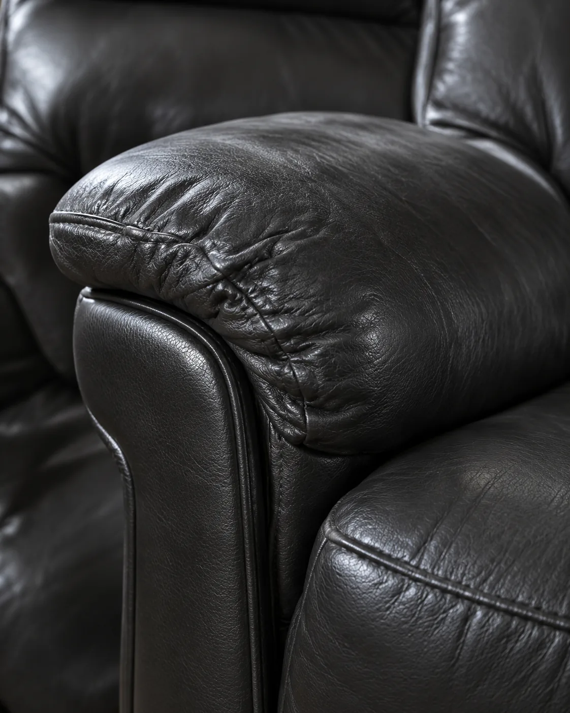 The padded arm of a black leather recliner