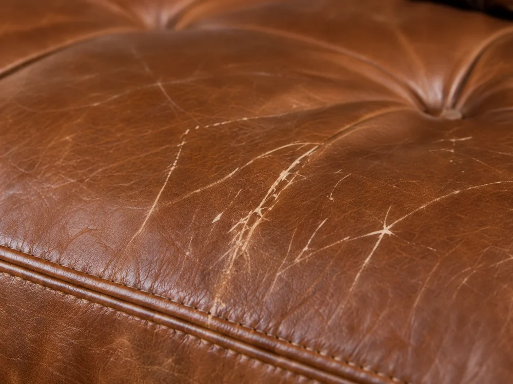 Brown leather seat cushion covered in fine surface scratches