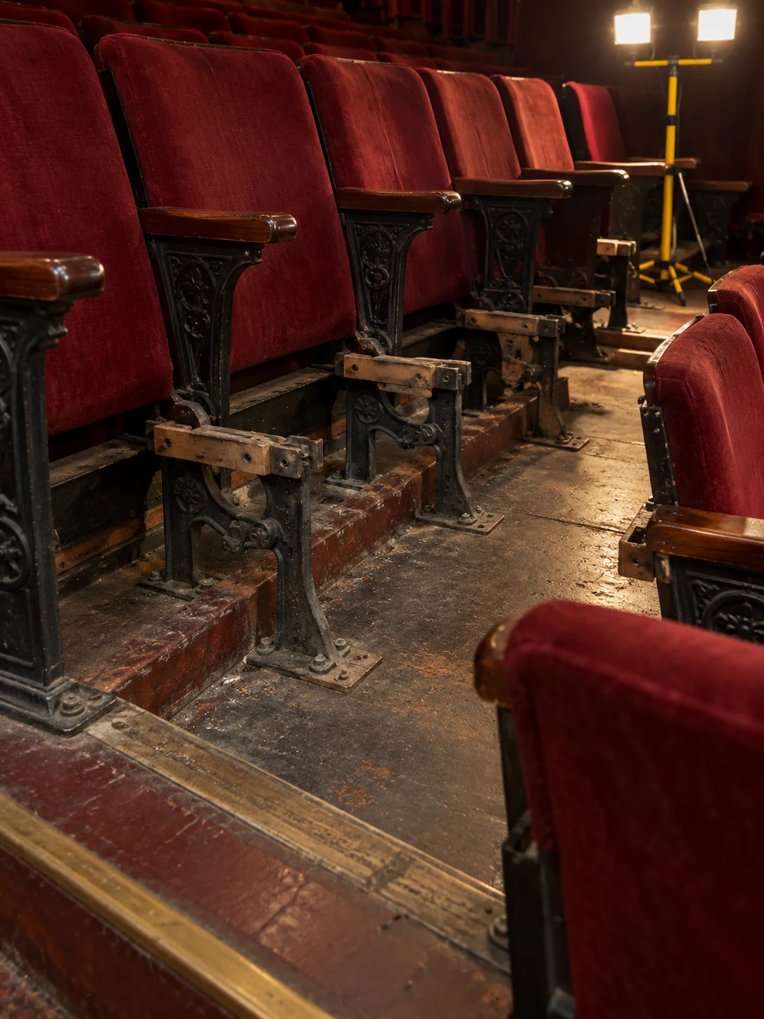 Seat pans removed from a row, cast iron standards still bolted to the floor