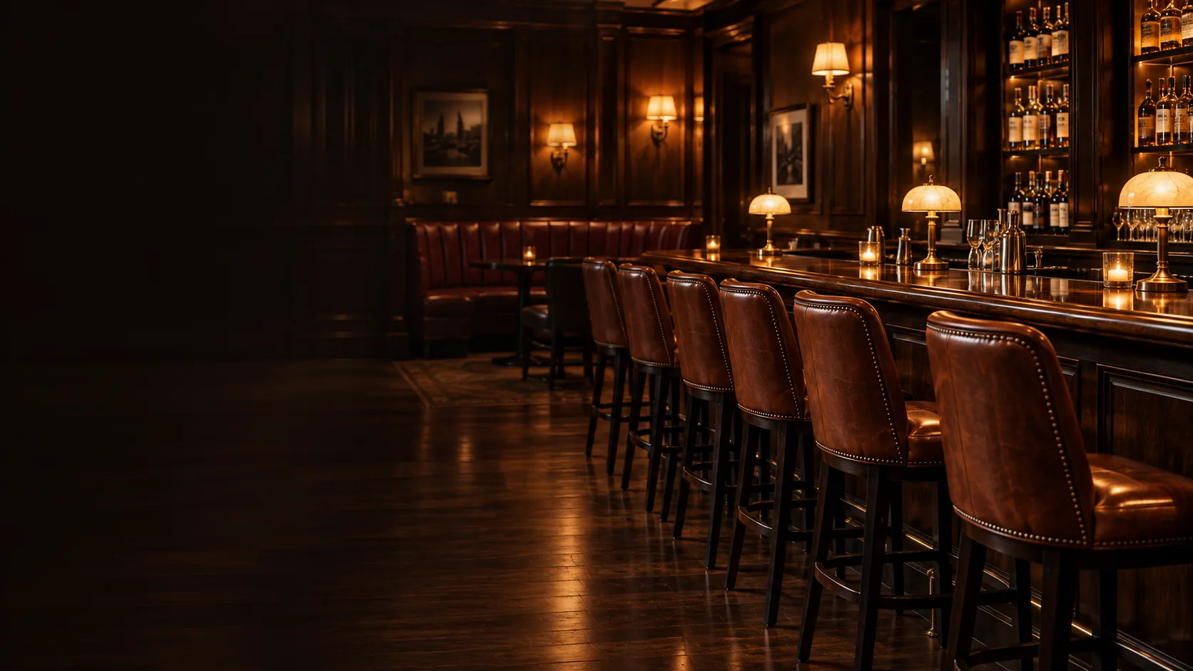 A quiet bar room after close, leather stools lined up along the lit back bar