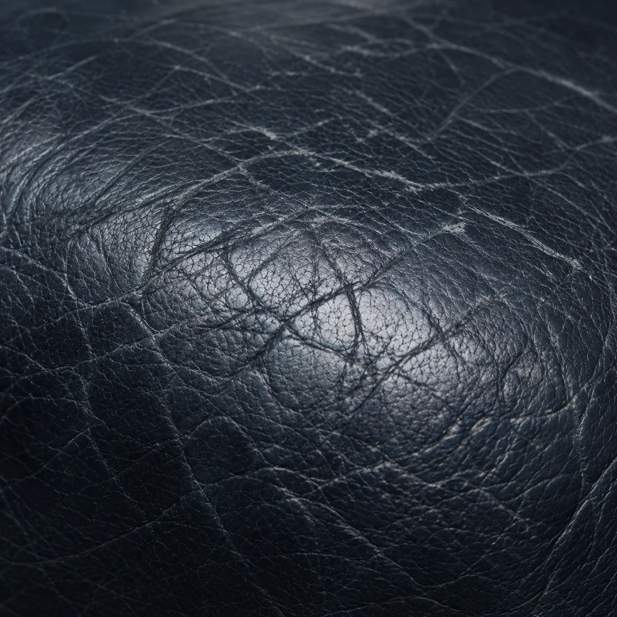 Crazed cracking across a dark navy leather seat