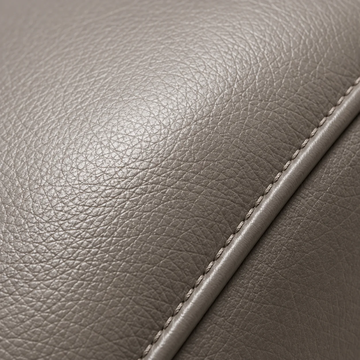 Close view of taupe leather grain beside a piped seam