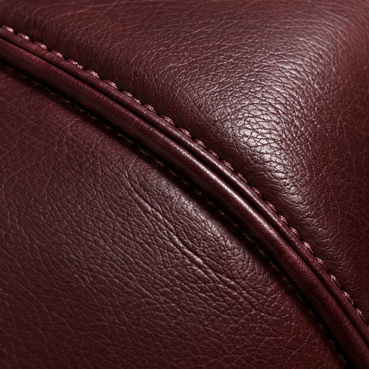 Close view of stitching along burgundy leather piping