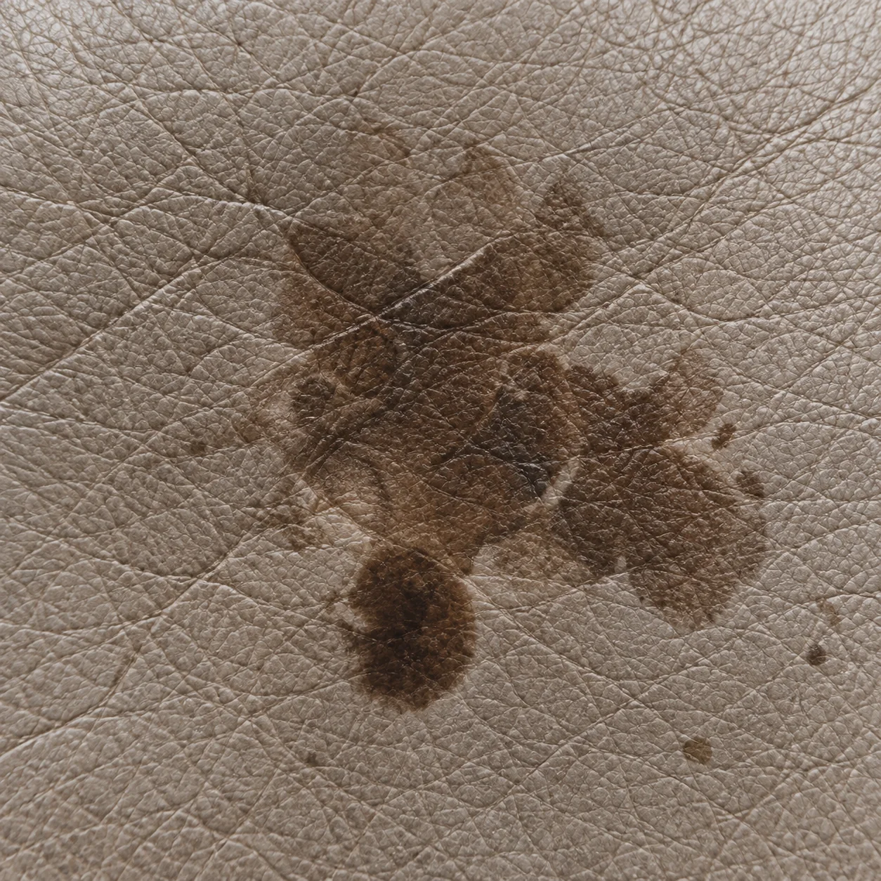 Brown staining soaked into a pale leather cushion