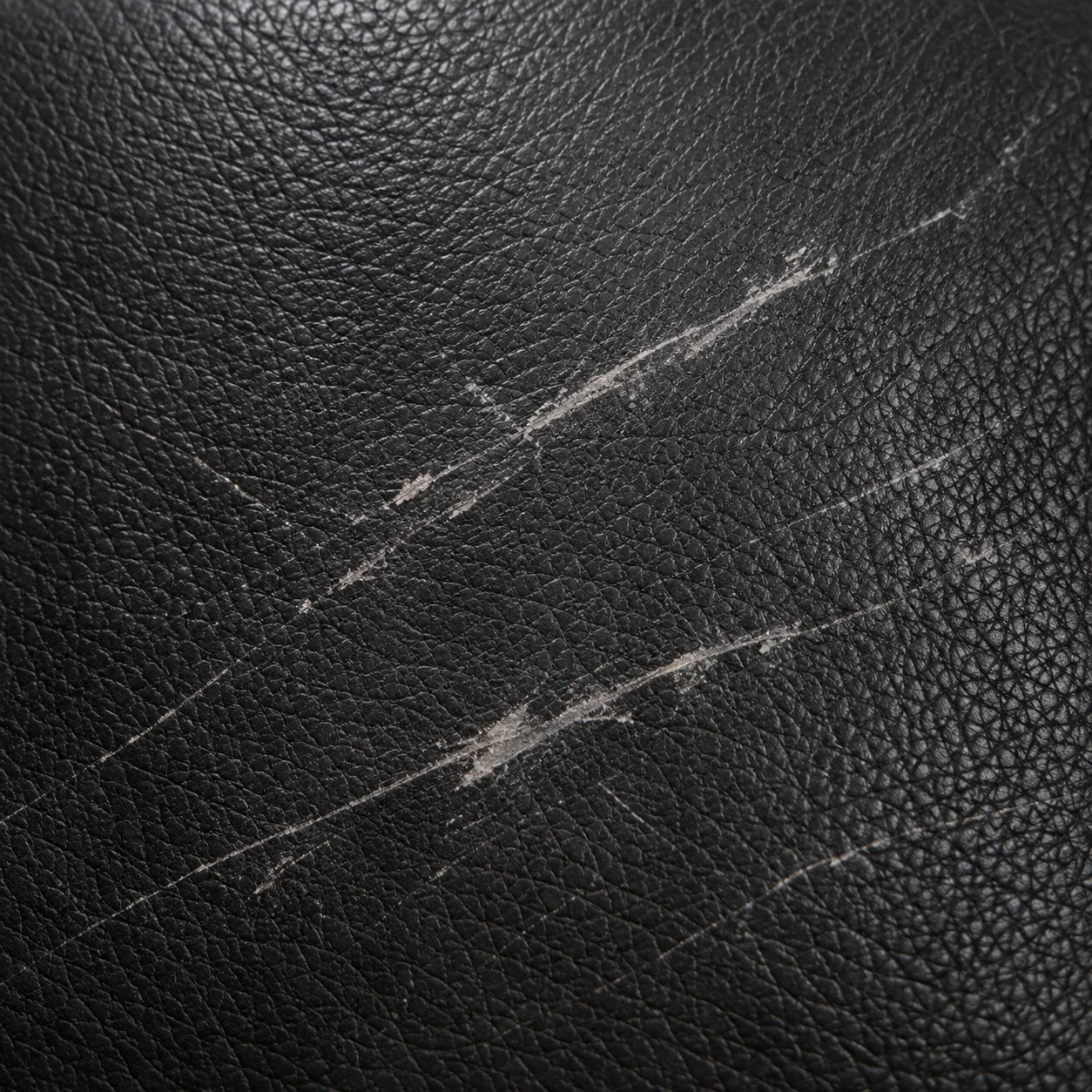 Scratches and scuffs on a dark leather surface
