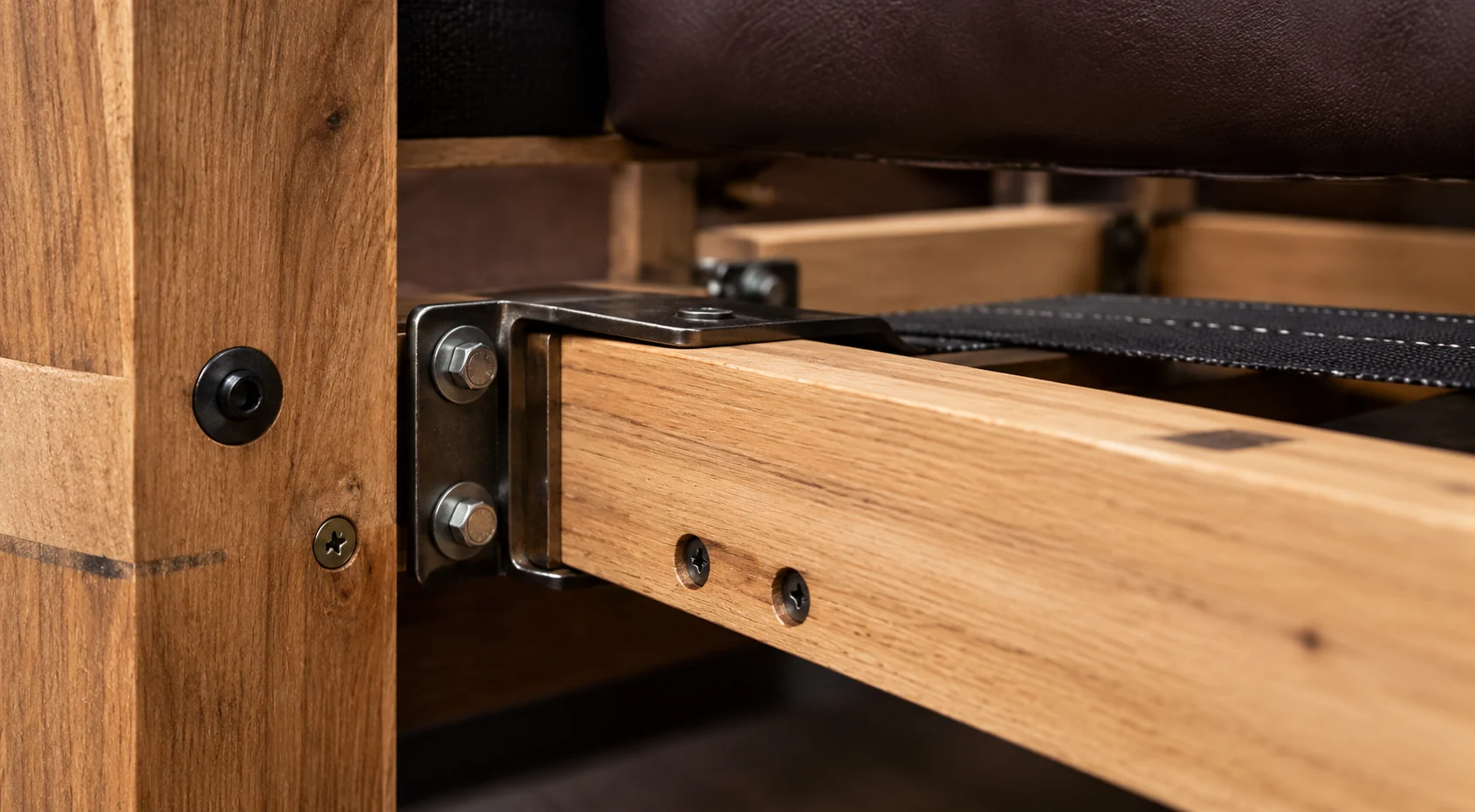 A timber bed side rail bolted to the post with a steel bracket and two bolts, slat support and webbing visible behind
