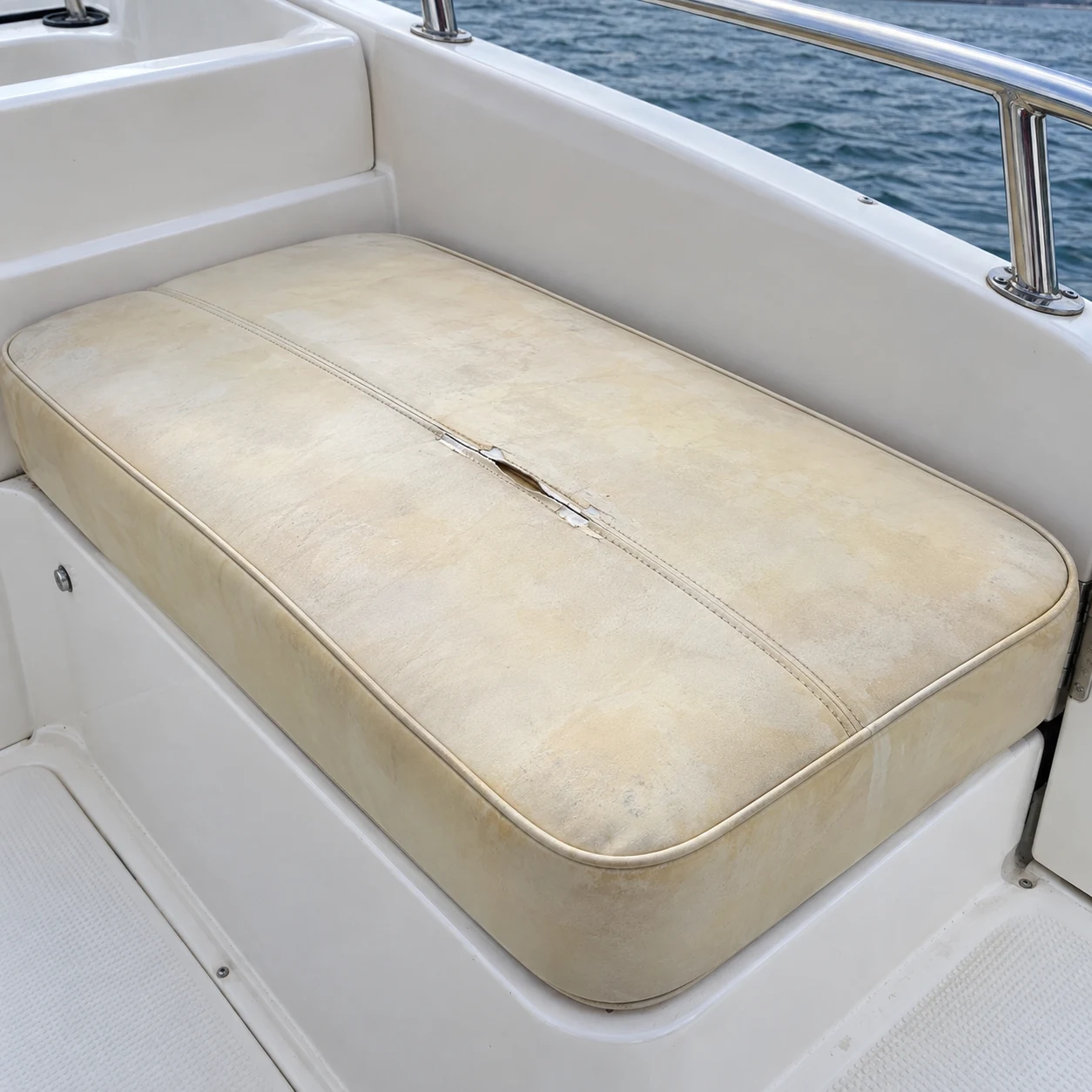 A faded, split boat cushion before reupholstery