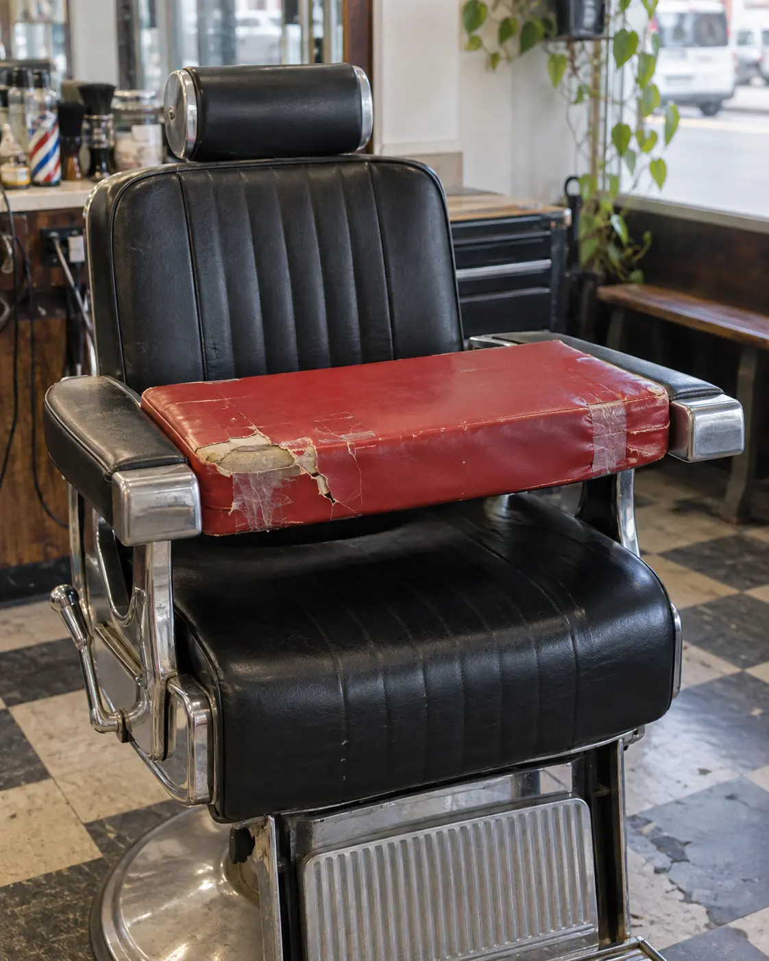 A torn red kids booster seat for a barber chair
