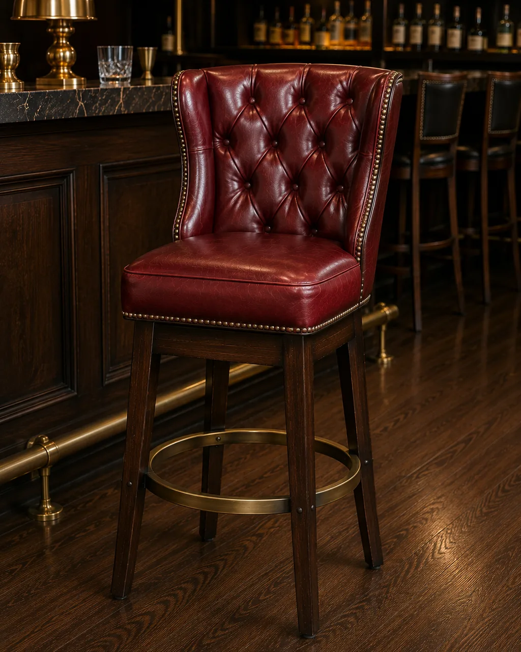 A bar stool in red leather with a tall buttoned back and studded edging, at a bar counter