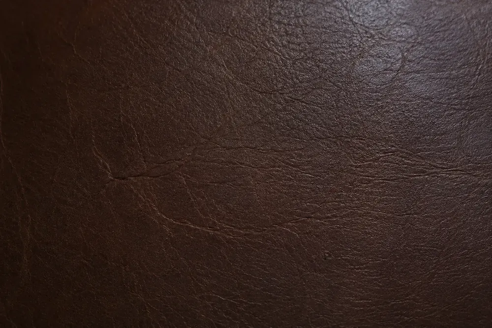 Dark brown leather panel covered in fine drag marks left by cat claws