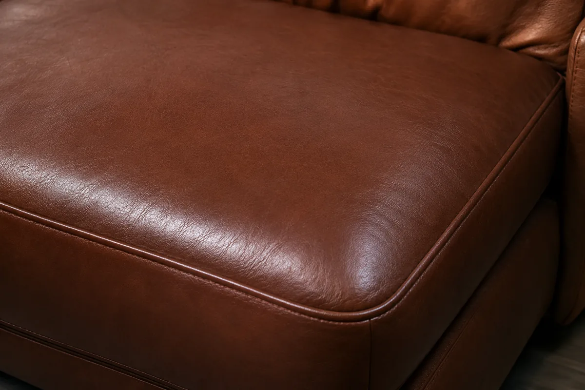 Finished brown leather seat cushion with the claw damage gone and the grain reading evenly across the panel