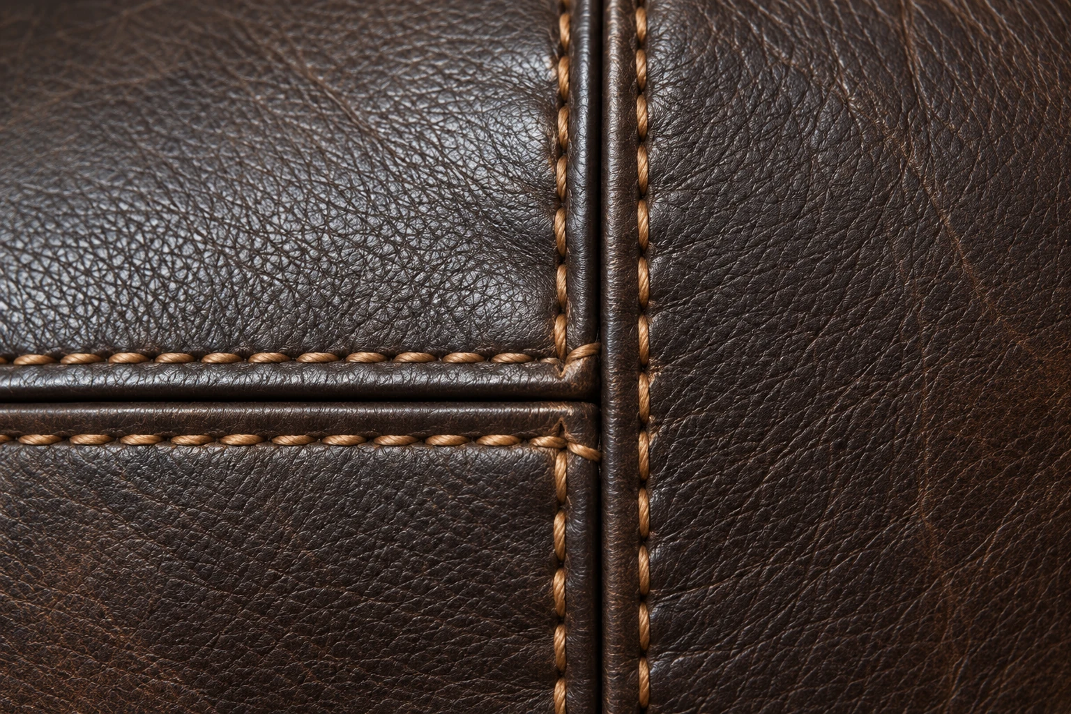 Dark brown leather panels meeting at a crossed seam with tan contrast stitching