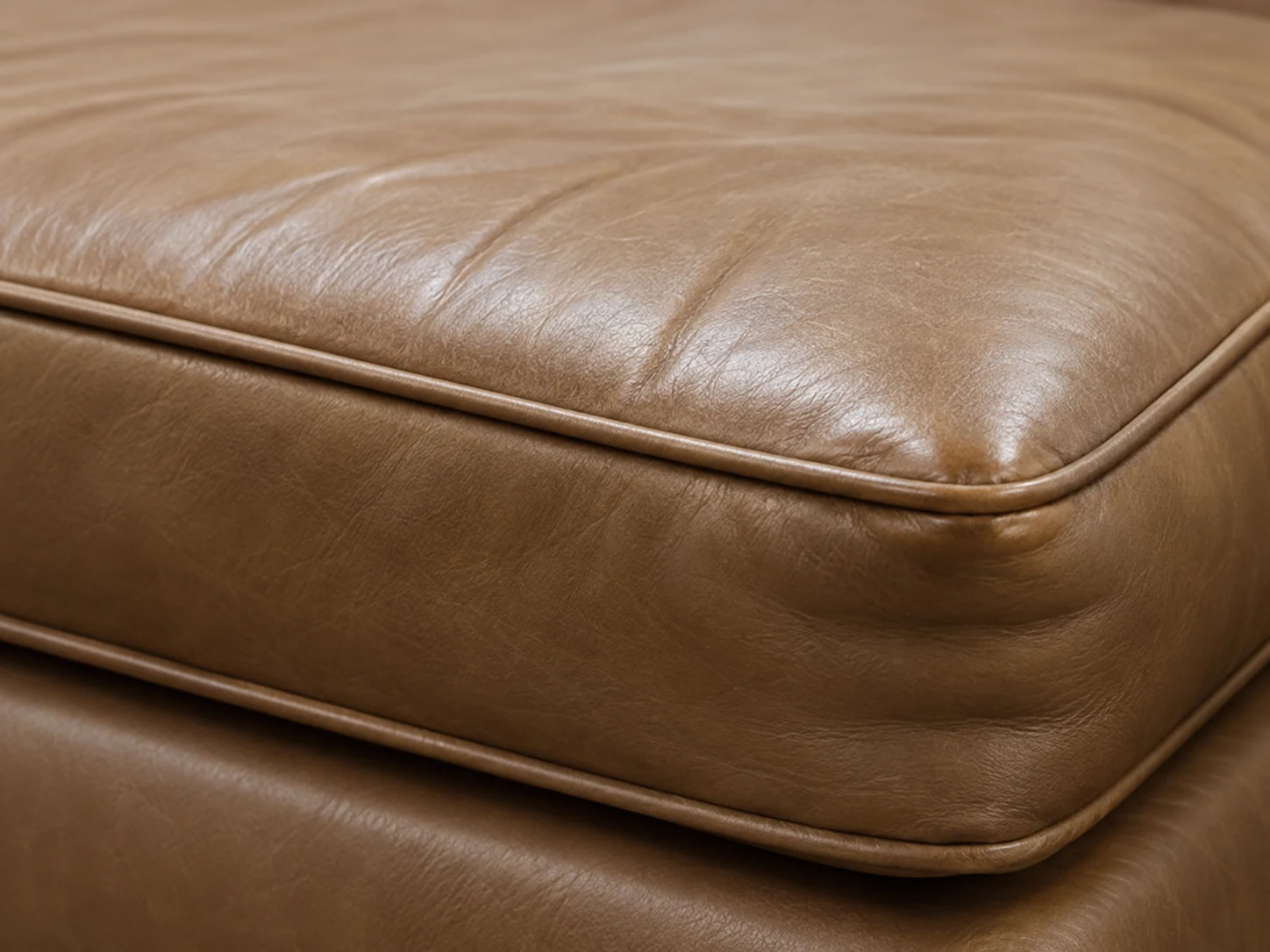 Collapsed front edge on a tan leather cushion with a broken welt line