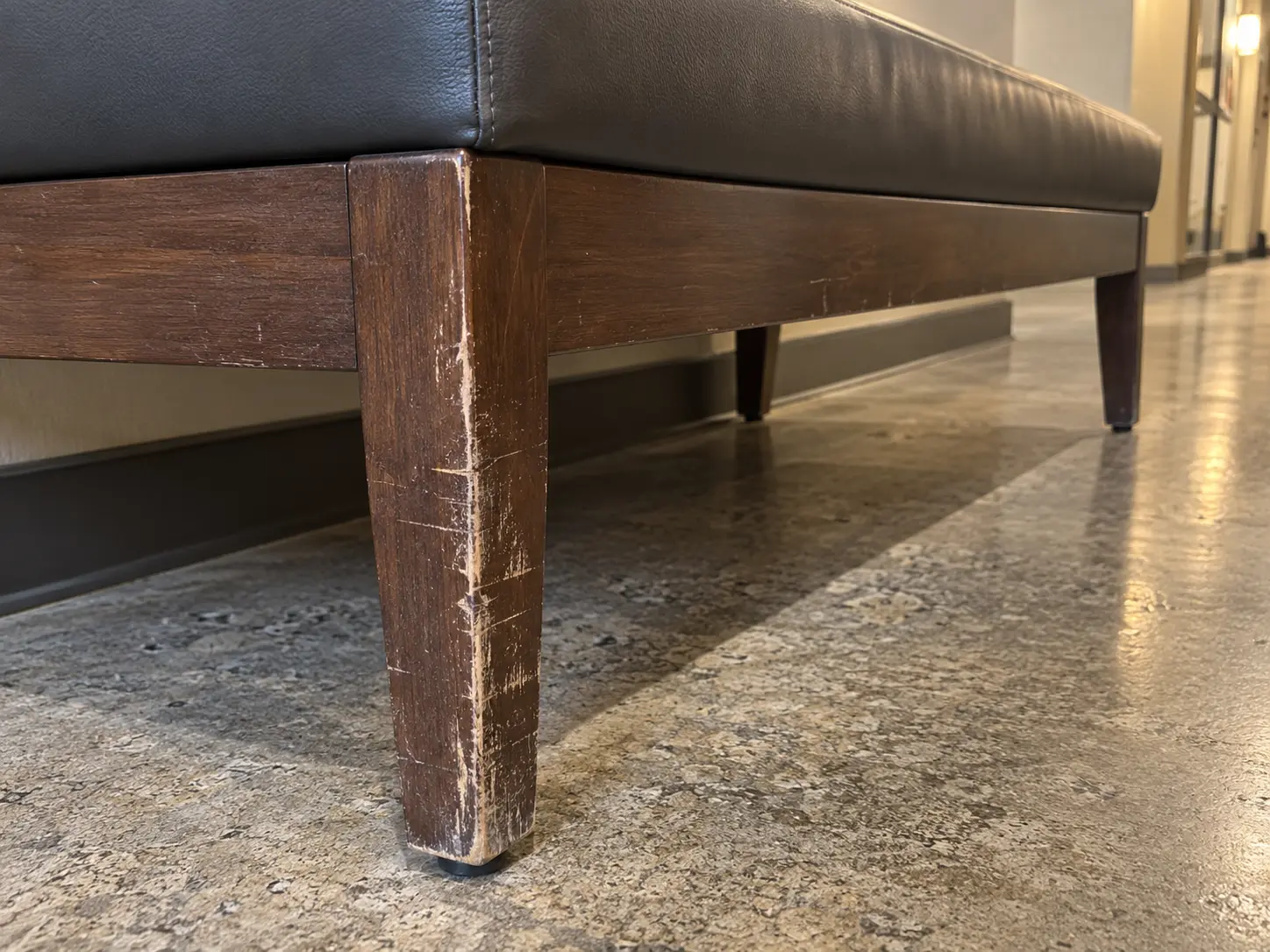 A scuffed wood frame on a common area bench