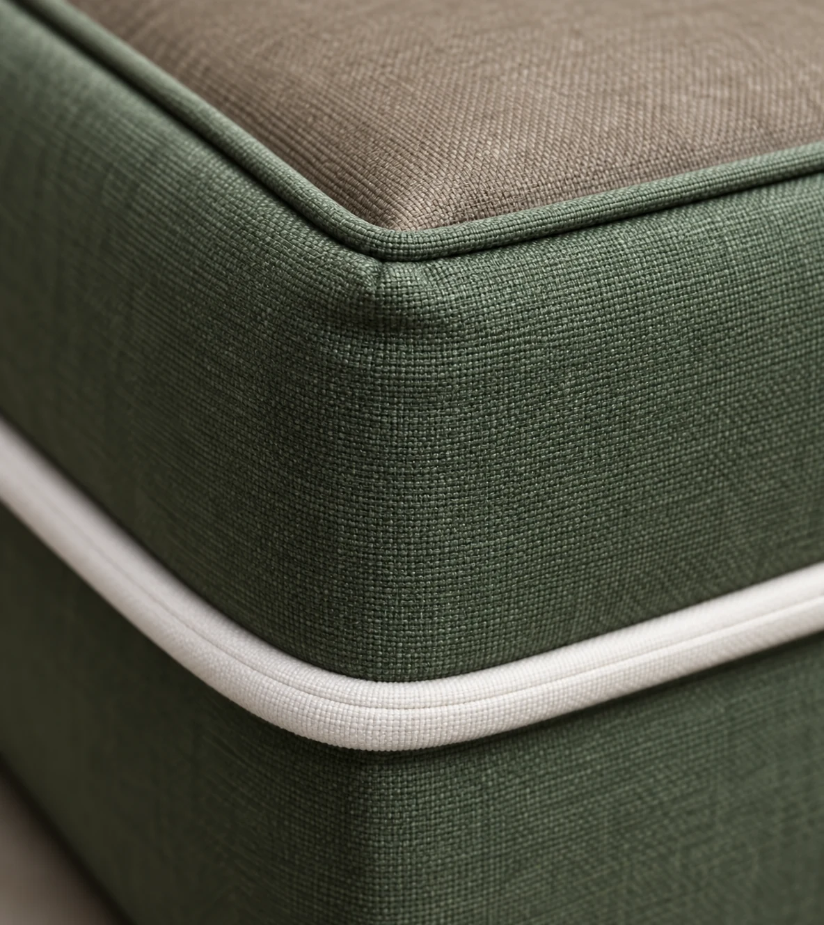 Cream contrast welt piping running along the corner of a green outdoor cushion