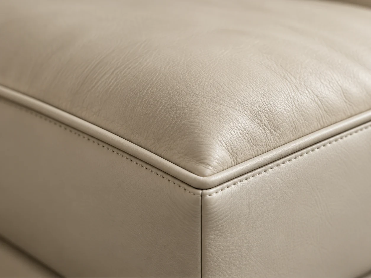 Squared front corner of a cream leather couch cushion