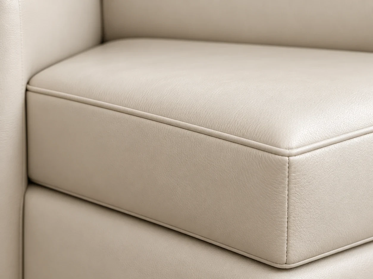 Cream leather couch cushion sitting flush against the arm of the couch