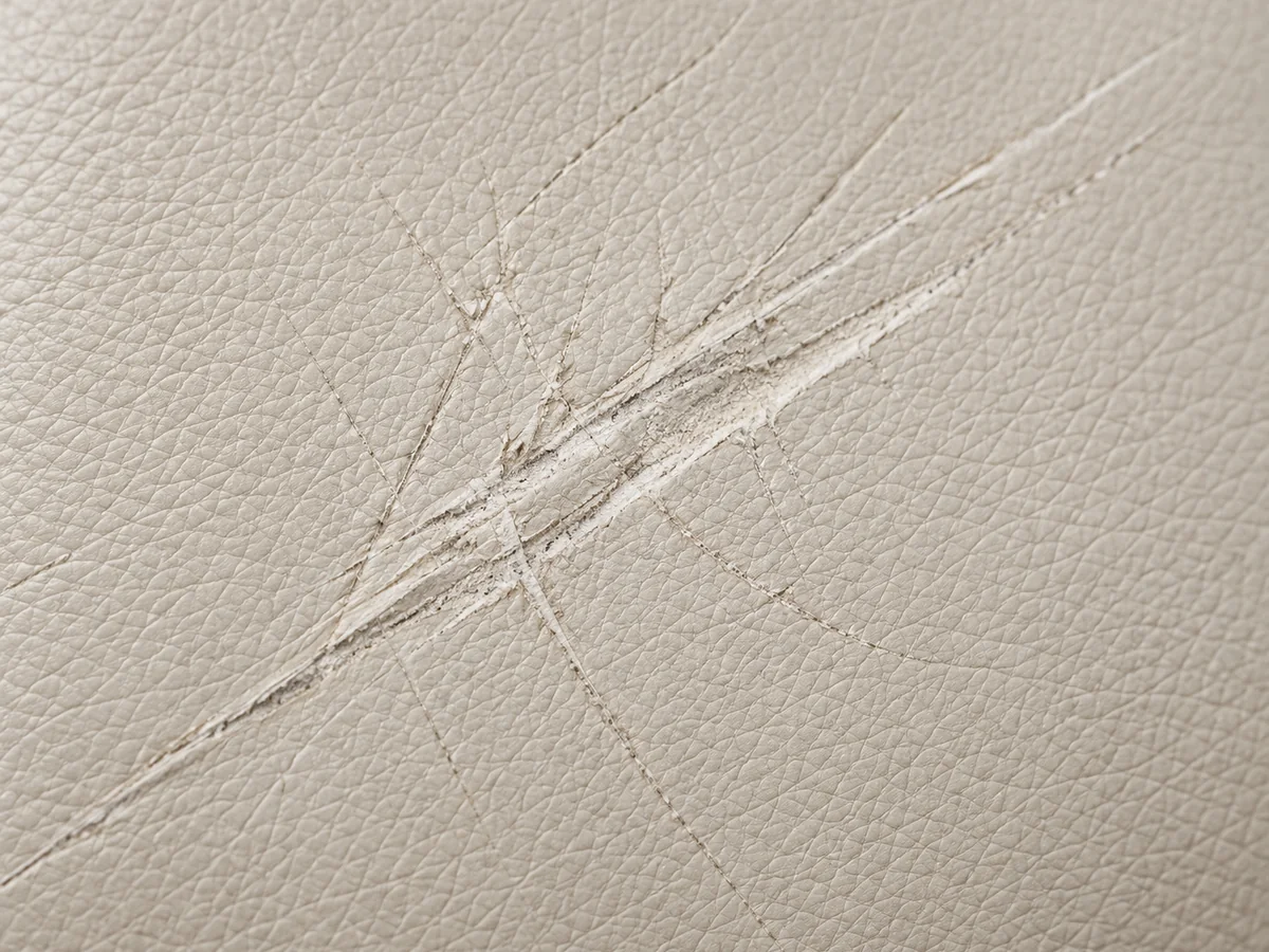 Deep scratches cut into a pale leather surface