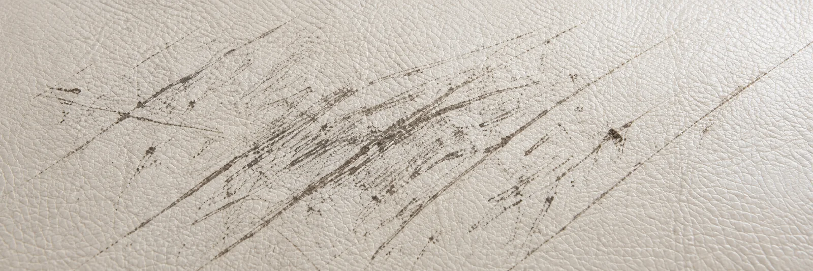 Scuffing and fine scratches raked across a pale leather panel