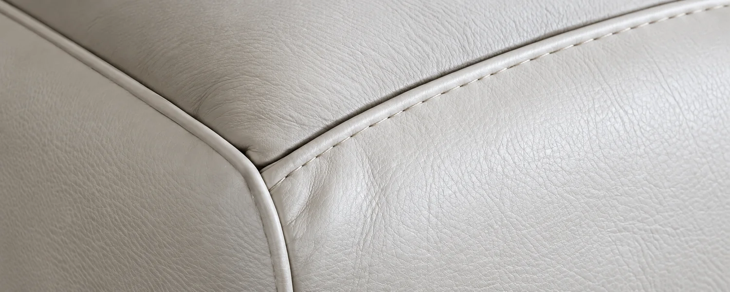 A cleanly fitted leather panel running along the piped edge of a cushion