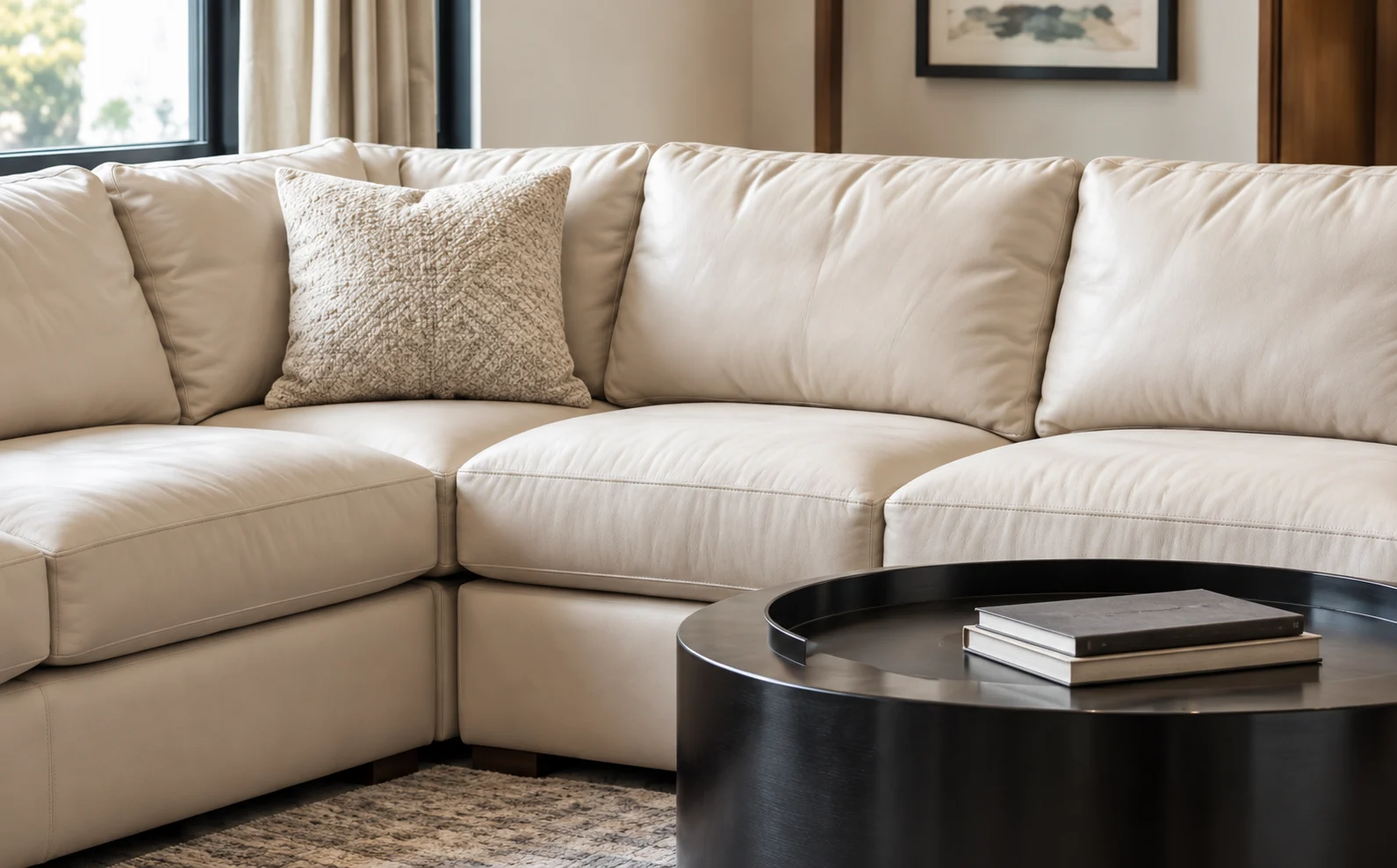 Cream leather sectional with a round black coffee table